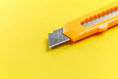 Foto de Un cuchillo de utilidad con una hoja segmentada retráctil sobre un fondo amarillo creativo de cerca. Herramienta de corte - Imagen libre de derechos