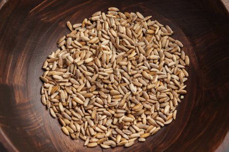 Milk thistle seeds in wooden brown bowl. Natural Source of Silymarin. Top view