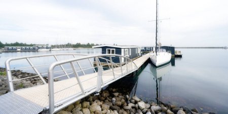 Ein Steg führt zu Ferienwohnungen und einem Segelboot auf dem Grevelingenmeer in den Niederlanden in der Nähe von bruinisse