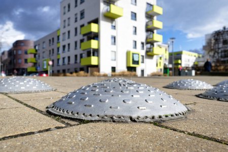 Nahaufnahme einer Geschwindigkeitsbeule im Stil des Kölner Teller-Schildes auf der Straße eines Wohngebiets