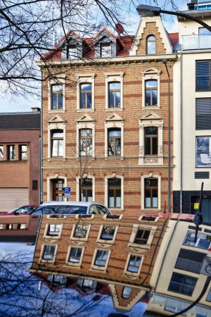 residential house from the end of the 19th century made of yellow brick and red decorations reflected on a car roof in cologne ehrenfeld