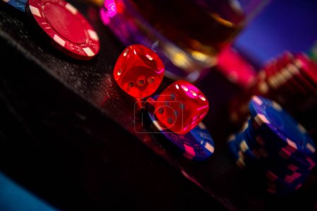 Photo for The dice sit on the gambling betting chips on a black wooden surface. Blurred background. Dice on blurred bokeh background. - Royalty Free Image