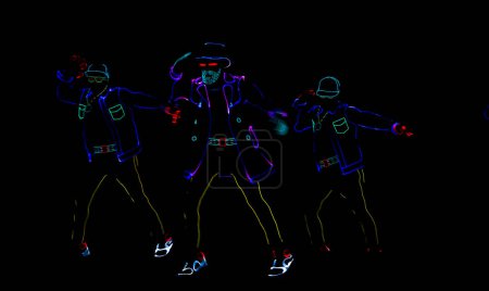 Silhouettes of people in luminous suits on a black background. Neon costume. Entertainment.
