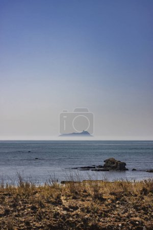 Photo for Ponza, Italy. The silhouette of the island emerging from the fog, seen from the Lazio coast in the distance. - Royalty Free Image