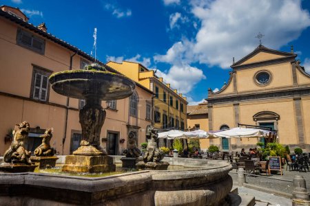 Téléchargez les photos : 2 juillet 2023 - Toscane, Viterbe, Latium. Un aperçu de l'ancien village médiéval de Toscane, ville des étrusques. La place avec l'église et la grande fontaine. - en image libre de droit