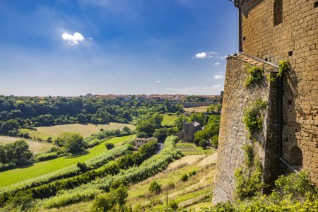 Téléchargez les photos : Tuscania, Viterbe, Latium. Vue sur l'ancien village médiéval de Toscane, ville des Étrusques, depuis le sommet de la colline qui s'élève en face de la ville. Campagne verte, riche en végétation. - en image libre de droit