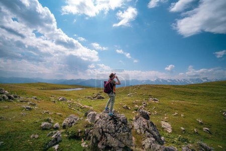Foto de Una mujer, un turista, un viajero está parado sobre una roca. Punto final de la ruta a pie a los lagos Koruldi, región de Svaneti, Georgia. Día de verano en las montañas del Cáucaso. - Imagen libre de derechos