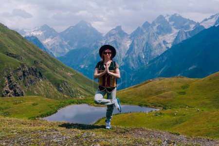 Photo for Young woman standing in the yoga position. Practices yoga. Koruldi lakes, Svaneti region, Georgia. Summer day in the mountains of the Caucasus. Spiritual mood and relaxation - Royalty Free Image