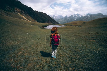 Téléchargez les photos : Une femme randonnée au lac Koruldi avec une vue imprenable sur les crêtes de montagne près de Mestia dans la chaîne de montagnes du Caucase, Haute Svaneti, Pays de Géorgie. La soif d'errance. Trekking - en image libre de droit