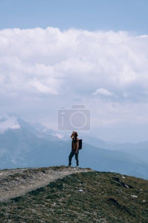 Téléchargez les photos : Femme en chapeau de soleil large et sac à dos, touriste sur la route de randonnée aux lacs Koruldi, région de Svaneti, Mestia Géorgie. Le concept de voyage et de loisirs actifs. Jour d'été. Photo verticale - en image libre de droit