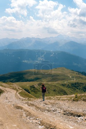 Téléchargez les photos : Femme en chapeau de soleil large et sac à dos, touriste sur la route de randonnée aux lacs Koruldi, région de Svaneti, Mestia Géorgie. Le concept de voyage et de loisirs actifs. Journée d'été.Photo verticale - en image libre de droit
