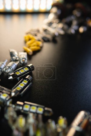 different headlight lamp on dark, black background. Modern diode, classic halogen and other lamp. Selective focus. Production and sale of electric car spare parts and accessories. Vertical photo