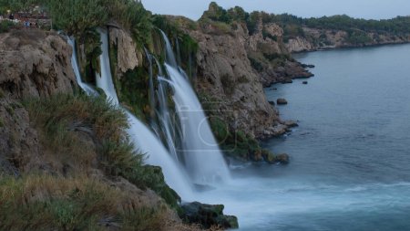Lower Duden Falls drop off a rocky cliff falling from about 40 m into the Mediterranean Sea in amazing water clouds. Tourism and travel destination photo in Antalya, Turkey.