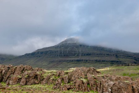 Islas Feroe. Una majestuosa montaña rodeada de pastos herbáceos en otoño, ligeramente nublado en la cima.
