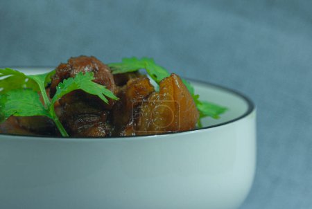 Téléchargez les photos : Vue rapprochée du plat traditionnel chinois de porc braisé. Bol en porcelaine blanche avec du porc braisé garni de feuilles de coriandre vert tendre. Préparation individuelle de la cuisine traditionnelle chinoise à domicile. - en image libre de droit