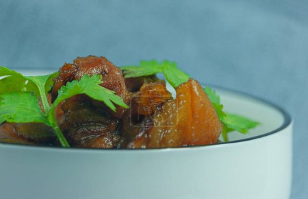 Téléchargez les photos : Vue rapprochée du plat traditionnel chinois de porc braisé. Bol en porcelaine blanche avec du porc braisé garni de feuilles de coriandre vert tendre. Préparation individuelle de la cuisine traditionnelle chinoise à domicile. - en image libre de droit