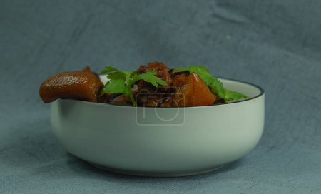Téléchargez les photos : Le cliché montre un plat traditionnel chinois fait maison, du porc braisé. Le bol en porcelaine blanche est au centre de l'image et contient du porc braisé surmonté de feuilles de coriandre vert tendre. Préparation individuelle d'un plat maison. - en image libre de droit