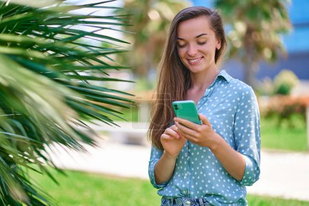 Téléchargez les photos : Jeune femme souriante heureuse utilisant le téléphone à l'extérieur. Personnes modernes avec un mode de vie de mobilité numérique - en image libre de droit