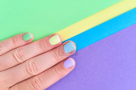 Téléchargez les photos : Doigts féminins avec des ongles d'été lumineux sur un fond coloré de près. Vue du dessus - en image libre de droit