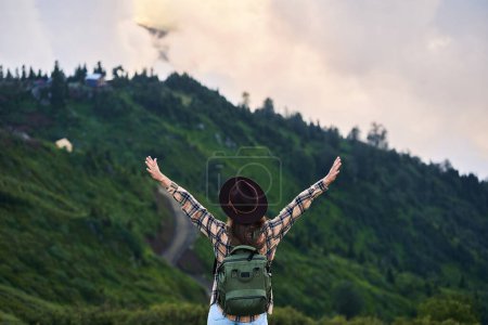 Téléchargez les photos : Femme d'inspiration libre touriste avec sac à dos se tient à bras ouverts et jouit de la tranquillité et de la tranquillité tout en voyageant dans les montagnes - en image libre de droit
