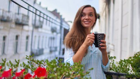 Photo for Portrait of beautiful happy smiling romantic woman with a cup of aromatic coffee resting and looking away on the balcony in the early morning in city - Royalty Free Image