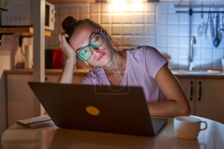 Téléchargez les photos : Sommeil femme surmenée de travail accro au casque s'est endormi sur le lieu de travail pendant le travail dur à l'ordinateur tard dans la soirée - en image libre de droit
