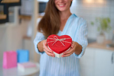 Foto de Feliz sonrisa satisfecha linda mujer amada sostiene una caja de regalo en forma de corazón para el día de San Valentín para el 14 de febrero - Imagen libre de derechos