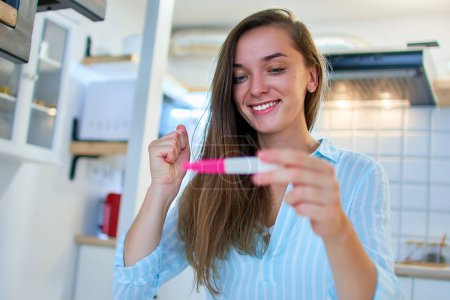 Photo for Happy cute satisfied young smiling woman rejoices in a positive pregnancy test result - Royalty Free Image