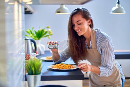 Photo for Smiling happy joyful cute cooking woman housewife salts and prepares a food for dinner - Royalty Free Image