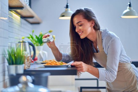 Foto de Sonriendo feliz alegre linda cocina mujer ama de casa sales y prepara una comida para la cena - Imagen libre de derechos