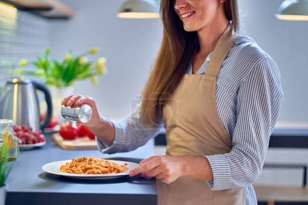 Photo for Cooking woman chef wearing apron salts and prepares food for dinner - Royalty Free Image