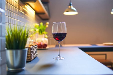 Téléchargez les photos : Verre à vin rouge debout sur une table dans une cuisine de style loft - en image libre de droit