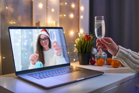 Téléchargez les photos : Les gens parlent en ligne sur appel vidéo virtuel et boire du champagne tout en célébrant la fête de Noël à distance sur un ordinateur portable à la maison. Vacances de Noël en ligne - en image libre de droit