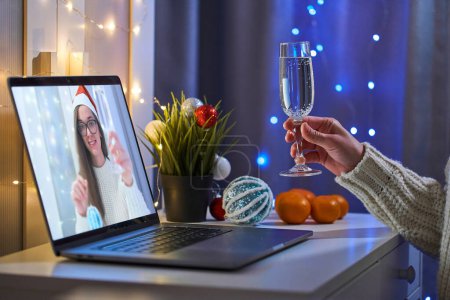 Foto de La gente aplaude y habla en línea en videollamada y bebiendo champán mientras celebra la fiesta de Navidad a distancia en una computadora portátil en casa. Vacaciones en línea - Imagen libre de derechos