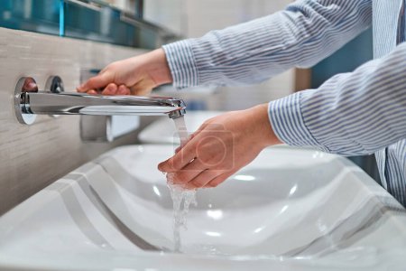 Foto de Persona lavándose las manos bajo el agua corriente en el baño - Imagen libre de derechos
