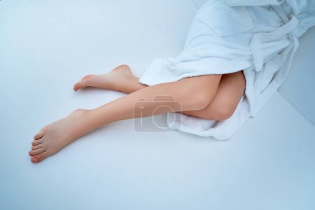 Téléchargez les photos : Femme portant un peignoir blanc avec de belles jambes longues lisses et fines - en image libre de droit