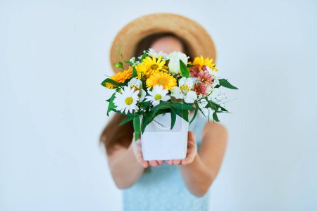 Téléchargez les photos : Femme tient décoratif coloré lumineux chapeau de fleur fraîche boîte au printemps - en image libre de droit