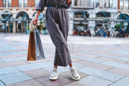 Téléchargez les photos : Femme élégante et à la mode accro au shopping avec des sacs en papier se promène dans le centre d'une ville européenne pendant la semaine de vente du vendredi noir - en image libre de droit