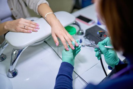 Téléchargez les photos : Femme dans le salon des ongles recevant manucure gel vernis par maître manucure. Soin doux des ongles - en image libre de droit