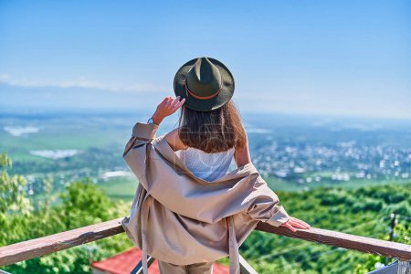 Photo for Traveler girl wearing felt hat standing alone and looking into the distance. Enjoying beautiful freedom moment life and serene quiet peaceful calm atmosphere in nature. Back view - Royalty Free Image