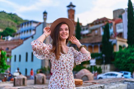 Téléchargez les photos : Joyeuse voyageuse souriante sur fond de bains de soufre dans le quartier Abanotubani de la vieille ville de Tbilissi, en Géorgie - en image libre de droit