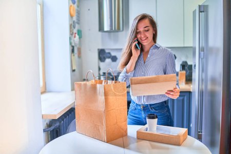 Photo for Modern busy casual cute adult happy smiling young woman customer received cardboard bags with takeaway food and drinks at home. Fast delivery service concept - Royalty Free Image