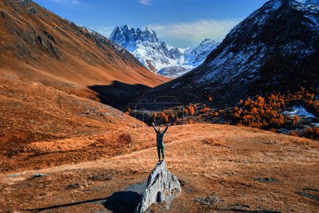 Foto de Viajero turístico mujer con los brazos abiertos de pie solo y disfrutando de la libertad y el paisaje inspirador valle de la montaña en la cima rocosa en Georgia - Imagen libre de derechos