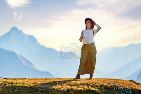 Photo for Serene peaceful young girl traveler backpacker wearing hat standing alone and enjoying freedom, silence and calm traveling - Royalty Free Image