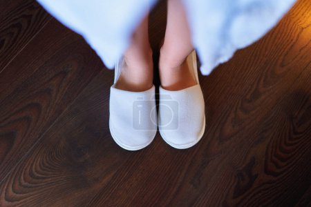 Photo for Female feet in white soft disposable hotel slippers - Royalty Free Image
