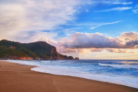 Téléchargez les photos : Paysage de paysage idyllique pittoresque calme fond d'écran ciel calme avec des nuages pelucheux, crête de montagne verte, côte de la mer et plage de sable fin - en image libre de droit