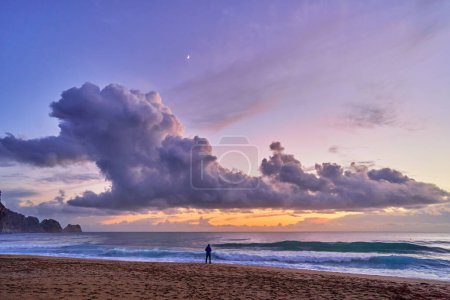 Téléchargez les photos : Paysage de paysage idyllique pittoresque calme fond d'écran ciel calme avec des nuages pelucheux et silhouette personne debout seul sur la côte de la mer et plage de sable - en image libre de droit