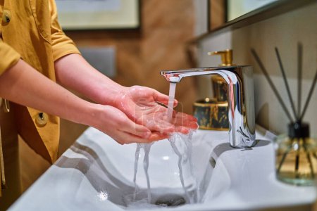 Téléchargez les photos : Se laver les mains sous l'eau courante du robinet dans le lavabo - en image libre de droit