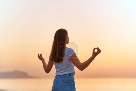 Photo for Back view of blissful serene satisfied one calm woman standing alone on the beach by the sea. Mental mind health care and relief moment - Royalty Free Image