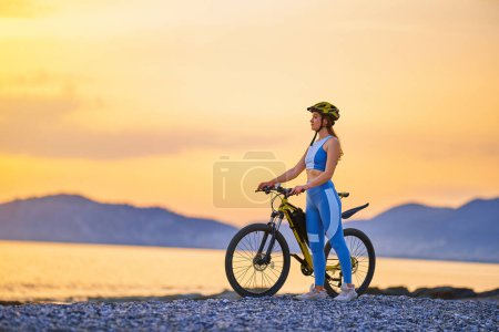 Foto de Mujer fitness joven activa que usa ropa deportiva y casco de pie solo con bicicleta al aire libre - Imagen libre de derechos